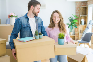 Fototapeta na wymiar Young beautiful couple very happy together holding cardboard boxes moving to a new home