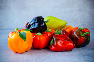Several multi-colored paprika on a gray background.