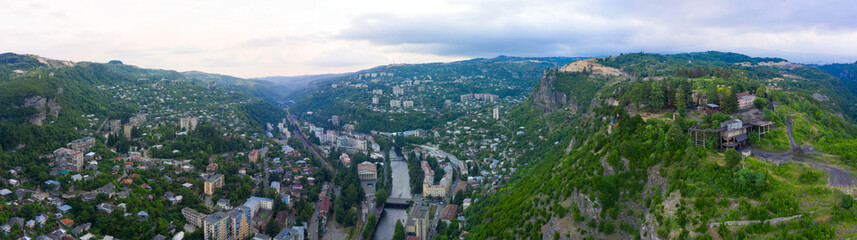 Old rusty and functioning ropeway or cable car cabins in Chiatura. Panorama of the city district and apartment buildings on the rock and Mine at Ropeway station Rgani.