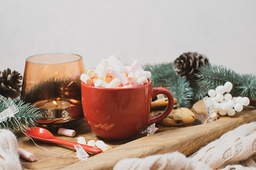 Christmas style composition with red cup of hot cacao with marshmallows, candles, fir tree and...