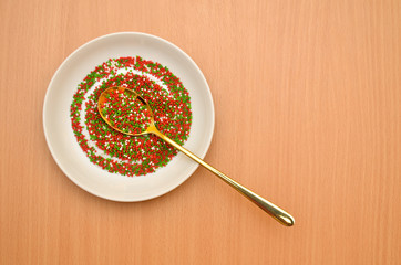 Round baking topping, sprinkle in a white saucer with golden spoon on a wooden table, top view