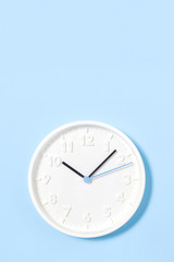 White analogue plain wall clock on trendy pastel blue background. ten oclock. Close up with copy space, time management concept and opening or start time daylight saving time