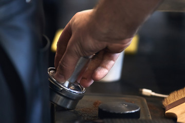 Coffee time. Barista holding portafilter and coffee tamper.