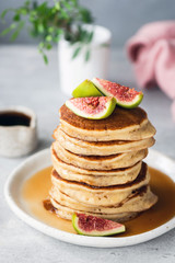 Stack of fluffy buttermilk pancakes with figs and maple syrup. Tasty sweet pancakes for breakfast