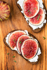 Figs and ricotta cheese rye bread toast. Healthy savory sandwich on wooden background