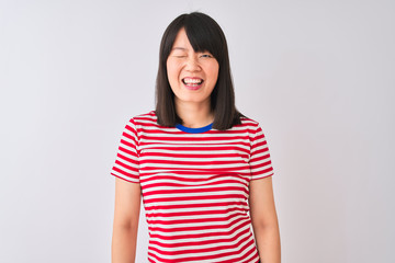 Young beautiful chinese woman wearing red striped t-shirt over isolated white background winking looking at the camera with sexy expression, cheerful and happy face.