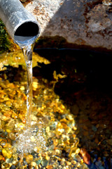 A stream of pure water flows out of the pipe and the bright sun shines.