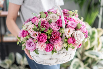 Flower arrangement in Wicker basket. Beautiful bouquet of mixed flowers in woman hand. Floral shop concept . Handsome fresh bouquet. Flowers delivery