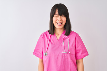 Young beautiful Chinese nurse woman wearing stethoscope over isolated white background winking looking at the camera with sexy expression, cheerful and happy face.