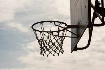Naklejka premium Closeup of a basketball hoop, basket with white net and blue sky with clouds in background