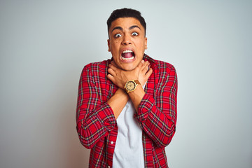 Young brazilian man wearing red shirt standing over isolated white background shouting and suffocate because painful strangle. Health problem. Asphyxiate and suicide concept.