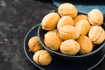 Homemade cookies in the form of nuts with boiled condensed milk on a black table