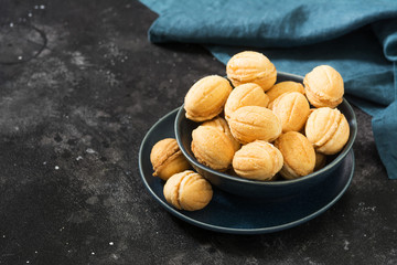Homemade cookies in the form of nuts with boiled condensed milk on a black table