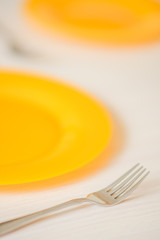 glass orange plates and forks closeup on the light wooden table.
