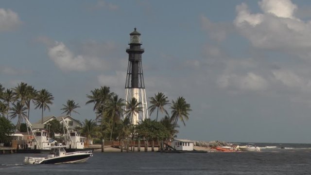 Pompano Beach Lighthouse at the Intracoastal Waterway at the Hillsboro Mile with a Boat Passing in a Spring Afternoon, Blue Sky with Scattered Clouds