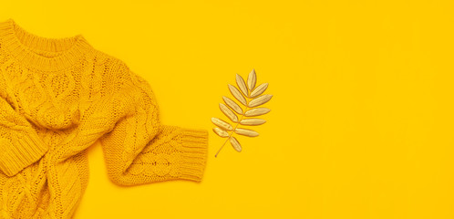 Autumn flat lay composition. Orange yellow knitted woolen female sweater and golden leaves on...