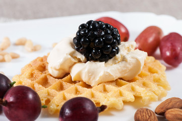Sweet waffles with sour cream and fruit on a light background.