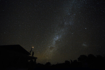 Naklejka na ściany i meble Couple on rooftop watching mliky way and stars in the night sky on Bali island
