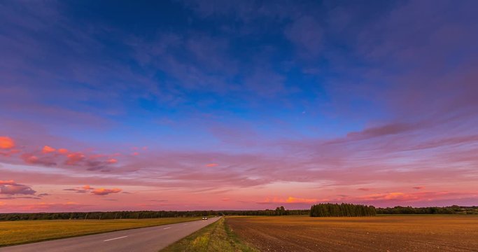 Red sunset sky time lapse with a road. Clouds timelapse nature background. Dramatic evening color beauty. Twilight, dusk dawn, summer.