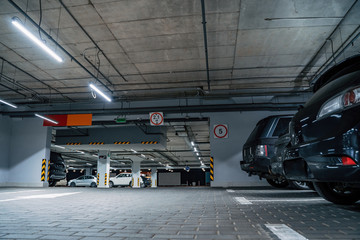 Illuminated underground car parking interior under modern mall with vehicles