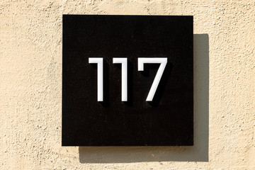 Number 117, one hundred and seventeen, street number sign on the wall	