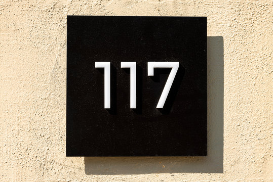 Number 117, one hundred and seventeen, street number sign on the wall	