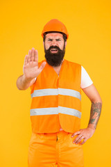 Caution, under construction. Hard worker showing caution sign on yellow background. Bearded man with caution hand gesture wearing protective workwear. Caution warning