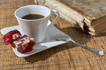 Turkish sweets with black coffee and book on the table.