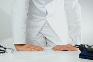 The doctor stands with his hands on the table. Medical and pharmaceutical concept. Conversation with patients, treatment. A man wearing a white coat treats patients.