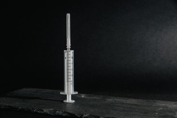 The syringe lies on a stone table top. Medical and pharmaceutical concept. Accepting injections, health problems. Treatment by injection of drugs into a syringe.