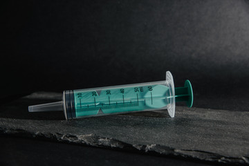 The syringe lies on a stone table top. Medical and pharmaceutical concept. Accepting injections, health problems. Treatment by injection of drugs into a syringe.
