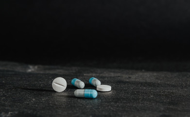 Medications, tablets are on a dark, black countertop. Medical and pharmaceutical concept. Help in taking medicine, regularity. Drug abuse.