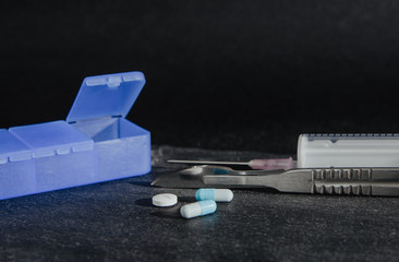 Medications, tablets are on a dark, black countertop. Medical and pharmaceutical concept. Help in taking medicine, regularity. Drug abuse.