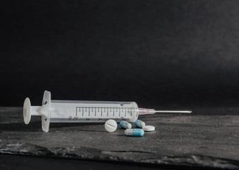 Medications, tablets are on a dark, black countertop. Medical and pharmaceutical concept. Help in taking medicine, regularity. Drug abuse.