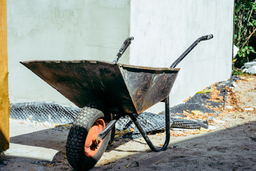 Wheelbarrow in front of the construction site. The concept of building, building a house, apartment. Equipment when building your own home. Renovation, improving the comfort of living in the apartment