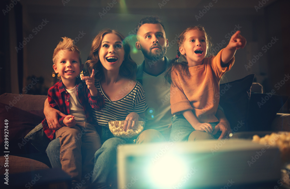 Wall mural family mother father and children watching projector, TV, movies with popcorn in   evening   at home.