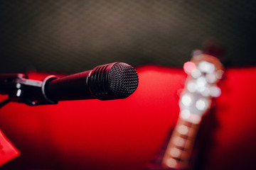 Recording microphone. Music concept. Record sound, music. Making music, recording. Creating sound foundations. Black microphone on a red background in the recording room.