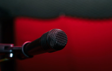 Recording microphone. Music concept. Record sound, music. Making music, recording. Creating sound foundations. Black microphone on a red background in the recording room.