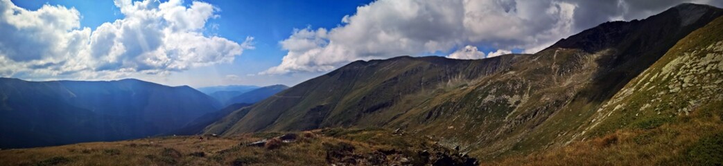 Alpine landscape with green mountains and blue sky covered with white clouds.   Fagaras - trail to the Lespezi Peak