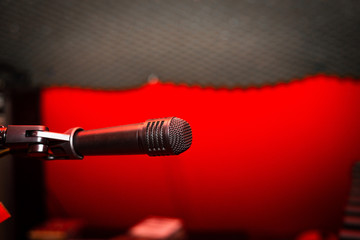 Recording microphone. Music concept. Record sound, music. Making music, recording. Creating sound foundations. Black microphone on a red background in the recording room.