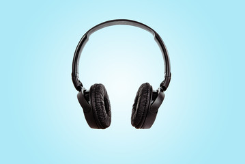 Black headphones on a pastel blue background. The concept of creating and listening to music. Comfortable headphones for listening to music. Creating sounds and listening to the foundations.