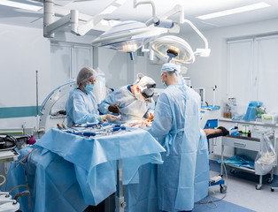 Spinal surgery. Group of surgeons in operating room with surgery equipment. Laminectomy