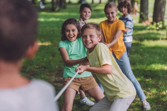 selective focus of cheerful kids competing in tug of war with african american boy