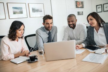Diverse businesspeople smiling while working together on a laptop