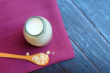 Vegan oat milk in a jar on dark wooden background. Image with copy space, top view