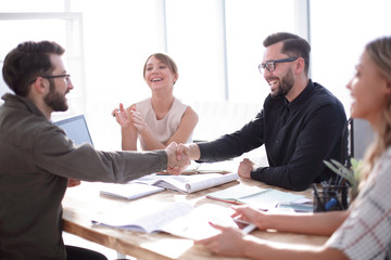 smiling business partners shaking hands at a business meeting.