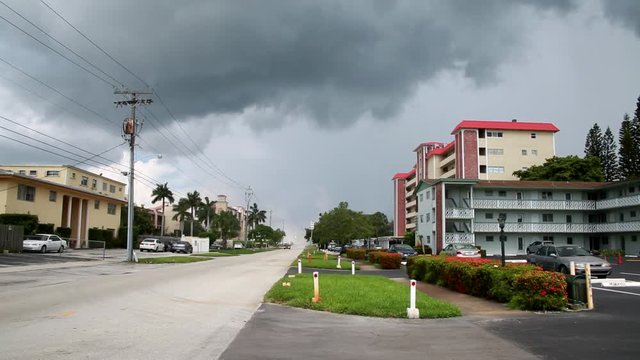 Big Rain Storm with Gray Clouds Approaching Condos on Street with Car Driving By in a Summer Morning in Pompano Beach, Florida