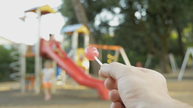 Kidnapper calls a little girl to himself, offering candy. Kidnapping. A stranger with candy in hand on the playground tries to theft a child. Child abduction or child theft.