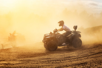Quad bikes driving in the sand .