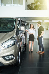 Young woman car sales consultant working in showroom